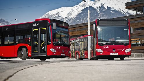 Zwei IVB-Busse mit schneebedeckten Bergen im Hintergrund