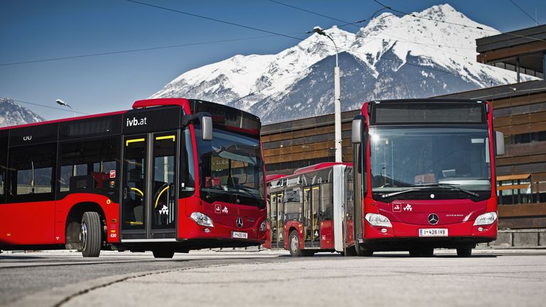 Zwei IVB-Busse mit schneebedeckten Bergen im Hintergrund