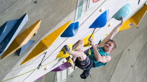 Ein Athlet an der Kletterwand. Zug um Zug