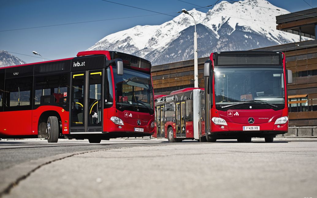 IVB-Busse an einer Haltestelle, beschneite Berge im Hintergrund